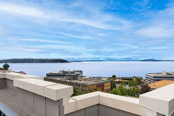 A view from a balcony overlooking a cityscape with buildings and a body of water.